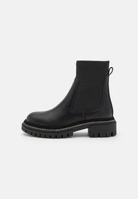 Botas negras hasta el tobillo con parte superior de cuero suave, paneles laterales elásticos, tira de agarre y suela de goma resistente con un borde decorativo metálico.