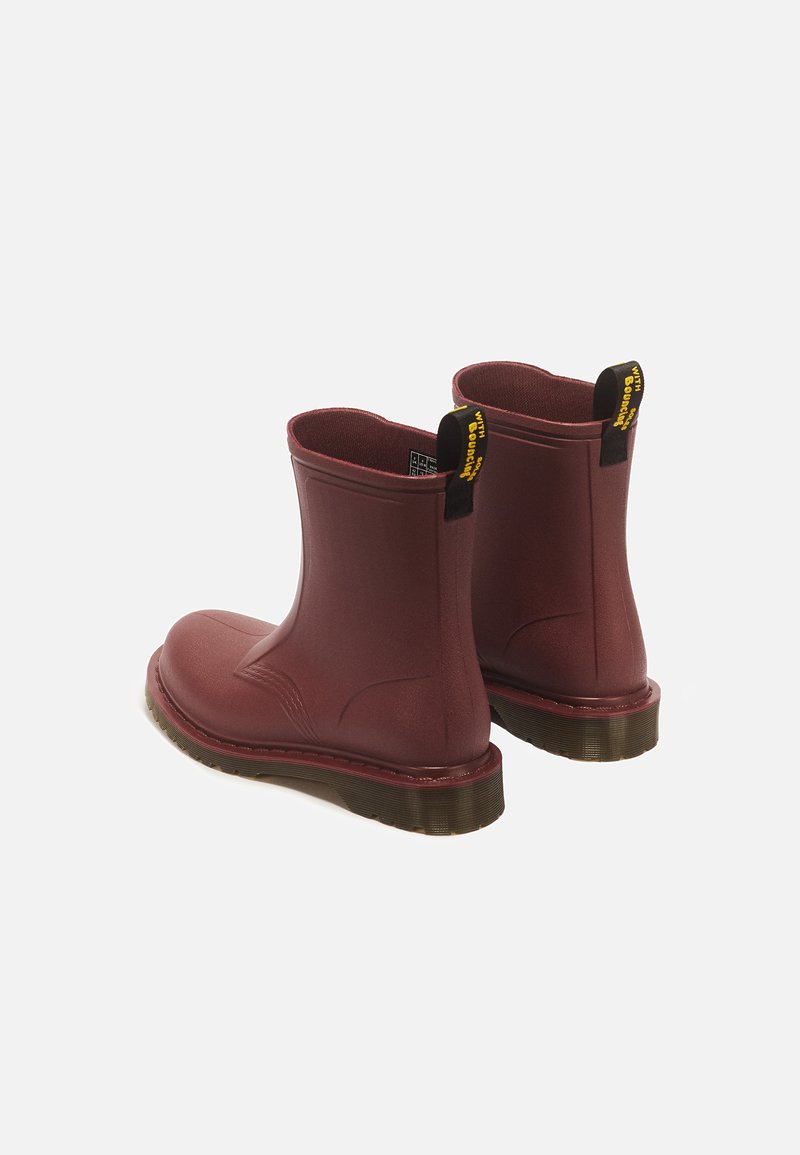 Paar dunkelrote knöchelhohe Regenstiefel mit schwarzen und gelben Zuglaschen und dicken braunen Sohlen auf weißem Hintergrund.