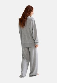Ensemble de vêtements d'intérieur gris en tissu doux, comprenant un pull ample à manches longues et un pantalon large pour le confort.