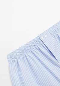 Boxers rayés bleu clair avec une taille élastique, présentant deux boutons blancs à l'avant et une texture lisse et douce.