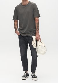Mörkgrå t-shirt med korta ärmar, kombinerad med smala mörka jeans. Tillbehör inkluderar en krämfärgad canvas toteväska och svarta sneakers.