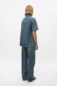 Denim shirt and pants set in light blue. Shirt has a collar, short sleeves, and side slits. Pants are wide-legged with a relaxed fit.