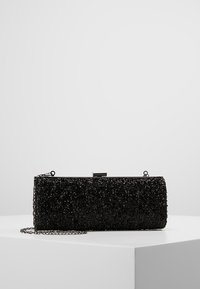 Pochette noire en matière texturée avec perles décoratives. Elle est dotée d'un fermoir argenté et d'une bandoulière chaîne amovible. Forme rectangulaire.