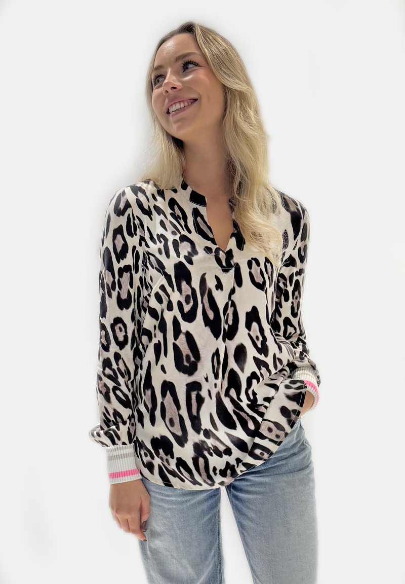 Leoprint-Bluse in Creme und Schwarz mit V-Ausschnitt, langen Ärmeln mit gerippten Bündchen in Grau und Pink sowie einer lockeren Passform.
