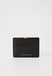 Black leather cardholder with textured surface, six card slots, and a small white, red, and blue accent stripe on the top. Branding displayed below.