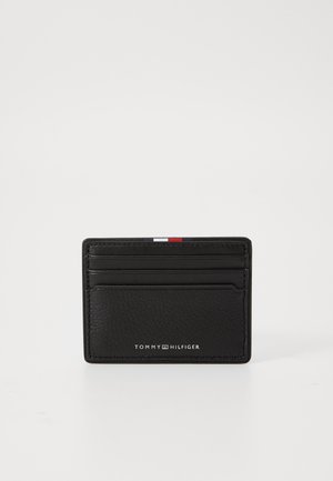 Card holder din piele neagră, cu suprafață texturată, șase sloturi pentru carduri și o mică dâra accent albă, roșie și albastră în partea de sus. Brandingul este afișat dedesubt.