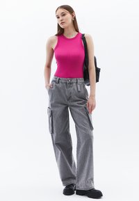 Tight rosa linne kombinerat med lösa grå cargobyxor med sidofickor och strukturerad textil. Svart ryggsäck fulländar looken.