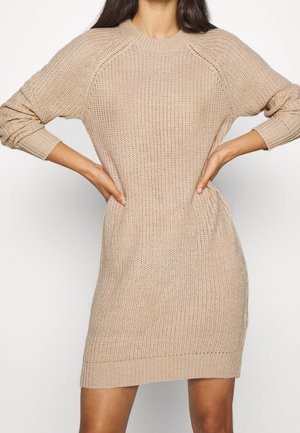 Gebreide jurk in beige met geribbelde manchetten en zoom, met een losse pasvorm en een gestructureerd patroon. Halflang met raglanmouwen.