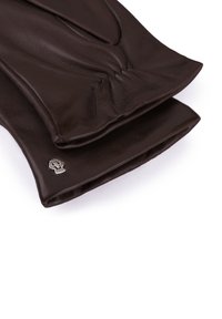 Braune Lederhandschuhe mit gerafften Details am Handgelenk und einem kleinen metallischen Totenkopfakzent nahe dem Bund. Glatte Textur.