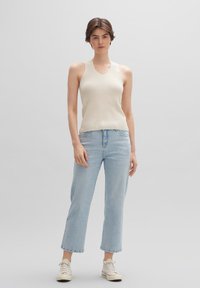 Crème ribben top met een ronde hals, gecombineerd met lichtblauwe rechte jeans en witte sneakers. Minimalistisch ontwerp met subtiele texturen.