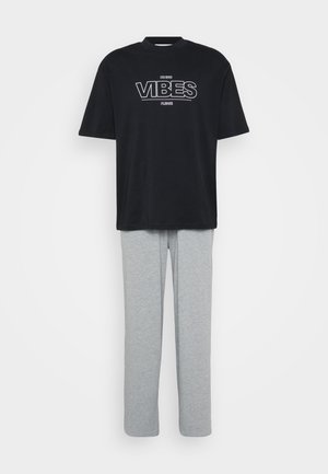 Melna kokvilnas T-kreklu ar "VIBES" uzrakstu baltā krāsā, savienots ar pelēkiem kokvilnas biksēm. Brīvā piegriezuma, īsām piedurknēm un taisnu kāju dizains.