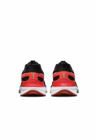 Zapatillas deportivas negras con un contrafuerte rojo y detalles en rojo, mediasuela blanca y parte superior de malla texturizada con detalles reflectantes.