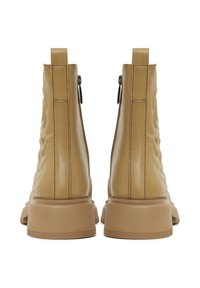 Barna bőrből készült bokaig érő csizmák, texturált felülettel, oldalsó cipzárokkal és vastag gumitalpakkal, sima felülettel és minimális varrási részletekkel.