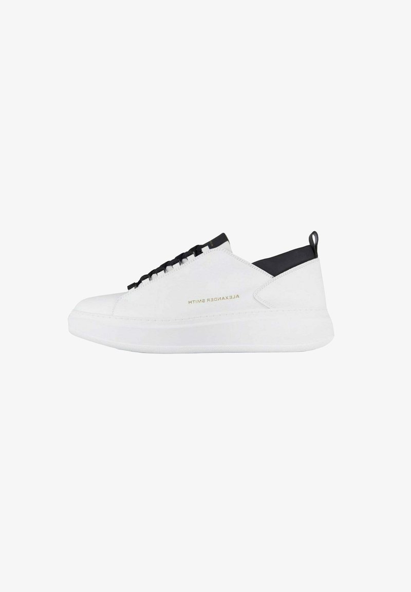 Zapatilla blanca de perfil bajo con cordones negros, lengüeta del talón negra y el logotipo dorado "Alexander Smith" en el lateral.