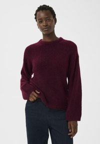 Pull en tricot bourgogne avec une coupe décontractée, col rond et manches longues. Sa texture douce et les détails de l'ourlet côtelé rehaussent le design.