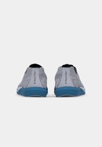 Baskets de sport en maille grises avec une semelle bleue, dotées d'un dessus doux et d'un design minimaliste, montrant la vue arrière et le détail du logo.