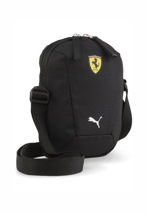 Sac noir compact à bandoulière avec sangle réglable, logo Ferrari en haut et logo Puma blanc en bas à l'avant.