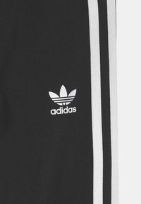 Pantaloni sportivi neri con strisce laterali bianche, con logo Adidas bianco sulla coscia sinistra, realizzati in un materiale morbido e elasticizzato.