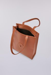 Borsa a tracolla in pelle di un caldo marrone con due manici lunghi, caratterizzata da un'apertura superiore e una texture liscia, che mostra un logo circolare su un lato.