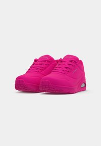 Svijetloružičaste Skechers atletske cipele s debelim potplatima, vezicama sprijeda i brend logotipima sa strane i na jeziku, prikazane na bijeloj pozadini.