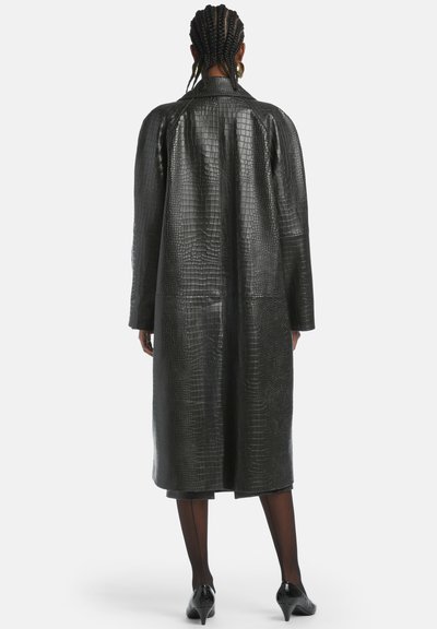 Kabát z černé kůže s embosovaným krokodýlím vzorem, s dlouhým, oversized střihem, vysokým límcem a splývavým zadním designem.