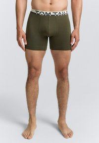 Grüne Boxer-Shorts aus Baumwollmischung mit passgenauer Form und einem Logo-Bund. Der Stoff wirkt glatt und hat keine sichtbaren Muster.