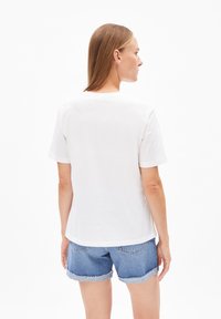 Witte katoenen t-shirt met korte mouwen, ronde hals en een ontspannen pasvorm, gecombineerd met denimshorts met omgeslagen mouwen.