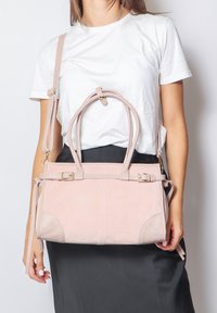 Borsa a mano in suede rosa chiaro con doppie maniglie e una tracolla staccabile. Presenta una forma rettangolare ed è impreziosita da accessori in oro.