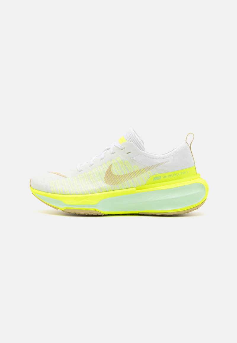 Baskets de sport blanches avec des accents jaunes, dessus en maille texturée et semelle translucide. Présente un logo Swoosh doré sur le côté.