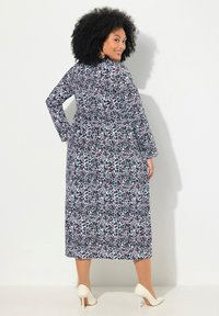 Langärmliges, knöchellanges Kleid in Marineblau und Weiß mit geometrischem Muster und roten Akzenten; leichter Stoff; tailliertes Design.
