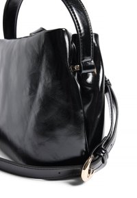 Bolso de mano de cuero negro brillante con asas redondeadas y una correa ajustable con hebilla dorada sobre un fondo blanco.