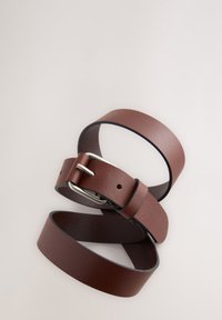 Cintura in pelle marrone dalla texture liscia, caratterizzata da una fibbia in metallo argentato e da molteplici fori per la regolazione, arrotolata su uno sfondo neutro.