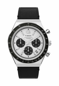 Montre chronographe à quartz avec un boîtier en acier inoxydable argenté, un cadran blanc, des sous-cadrans noirs et un bracelet en cuir noir. Elle est dotée d'une échelle tachymétrique.