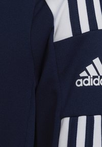 T-shirt de sport bleu marine avec un tissu texturé, des accents blancs, trois bandes verticales sur la manche et un logo Adidas blanc.