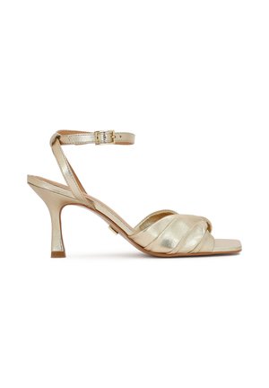 Sandale aurii din satin cu toc înalt, design curbat, vârf deschis și curea ajustabilă în jurul gleznei cu o cataramă dreptunghiulară.