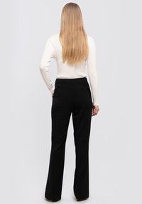 Black flared trousers with a smooth texture and a tailored fit, featuring a single back pocket and high waist design.