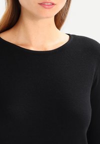 Black long-sleeve top, knit texture, round neck, fitted design, smooth fabric with slight sheen, no visible patterns or accents.