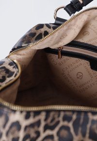 Väskan i leopardmönster har gulddragkedja, svarta läderdetaljer och en beige inredning med logomönster samt ett litet fickor med dragkedja.