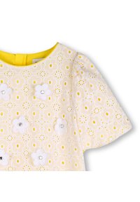 Vestido blanco con bordado floral amarillo, con flores de tela decoradas con detalles de rhinestones, mangas cortas abullonadas y escote redondo.