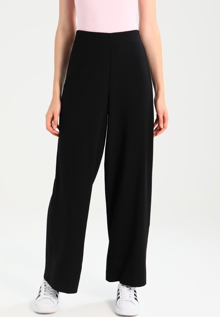 Pantalon noir à jambes larges en tissu lisse et léger, taille haute. Conçu avec un style simple et épuré, sans fermetures visibles.