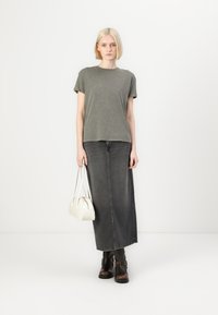 Olive green short-sleeve T-shirt, gray maxi skirt, black ankle boots, white handbag. Simple design with a relaxed fit and smooth texture.