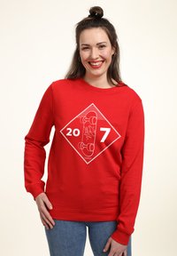 Červená mikina s bílým grafickým designem se čísly "20" a "7", zdůrazňující skateboard v diamantovém tvaru.