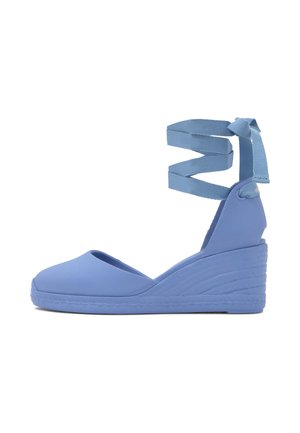 Alpargata azul con cuña, cintas para atar alrededor del tobillo anudadas en lazo, puntera cerrada y suela texturizada.