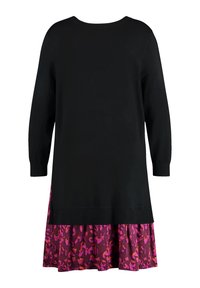 Robe en maille noire à manches longues, avec une jupe à volants à motifs floraux violets. Texture lisse et encolure ronde.