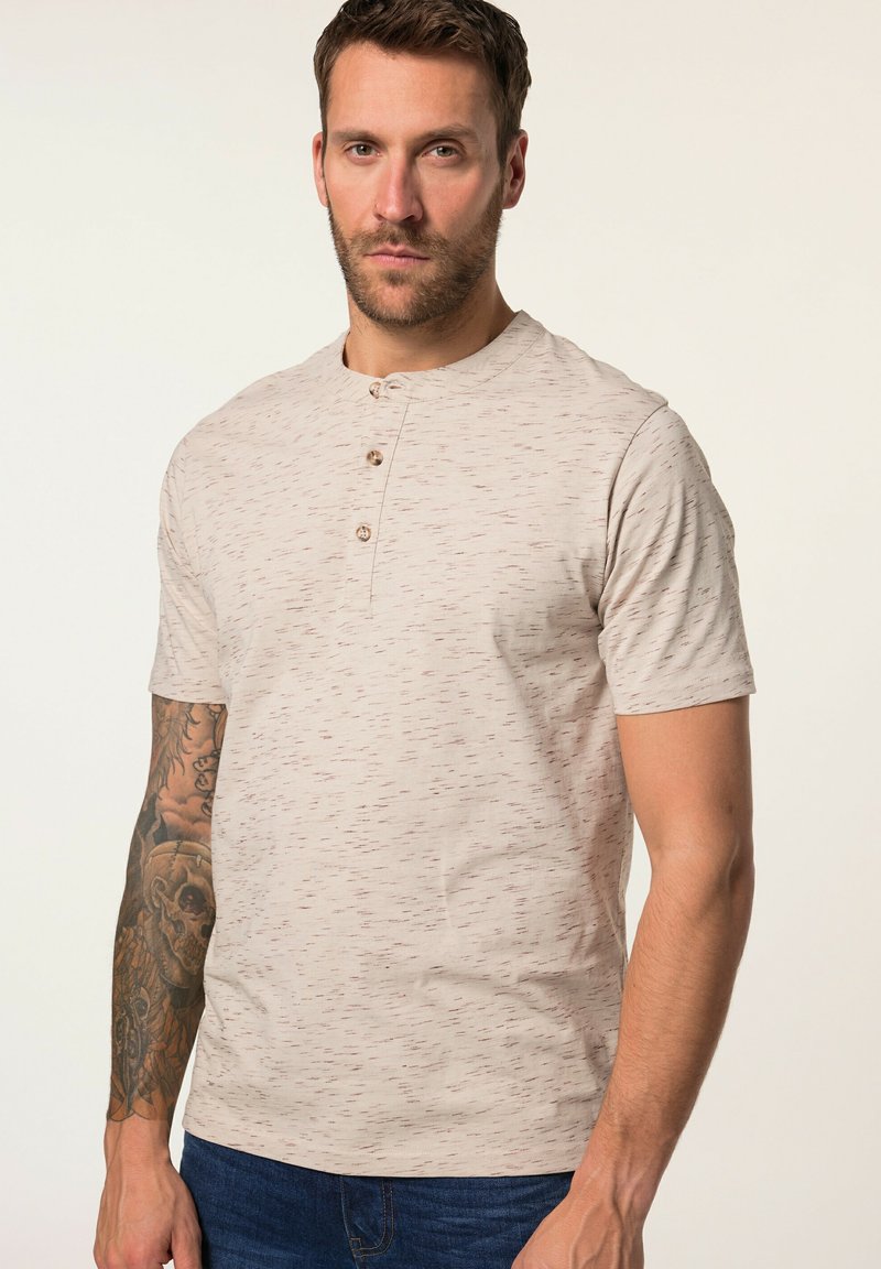 Camisa henley de manga corta en color beige claro con un patrón texturizado, tres botones en el cuello y un corte relajado. Ideal para un estilo casual.