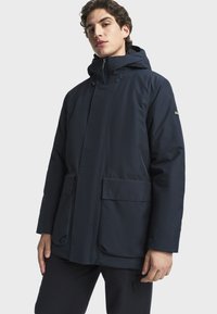 Námornícky nepremokavý parka s kapucňou, dvoma veľkými prednými vreckami, zipsom a nastaviteľnými sťahovacími šnúrkami. Hladká textúra, minimalistický dizajn.