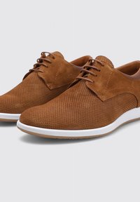Zapatos de ante marrón con cordones que presentan una parte superior perforada, suela de goma blanca y acentos de cuero en contraste en el talón y el cuello.