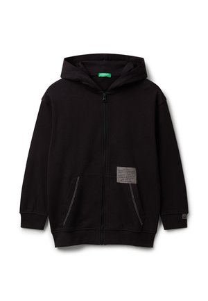 Haut hoodie noir zippé avec poches avant, une capuche, des détails de couture blanche et un petit patch texte carré sur la zone de la poche droite.