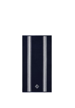 Serviette bleu marine avec deux ensembles de rayures blanches parallèles et un petit logo blanc brodé près du centre inférieur.