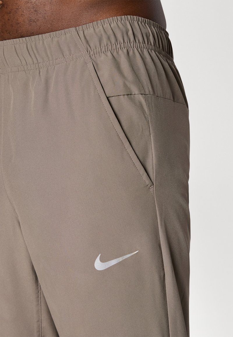 Nike träningsshorts, gjorda av ljusbrunt tyg, med en elastisk midja, sidoficka och en silverfärgad logotyp.